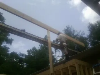 Carpenter setting a ridge beam over a new addition frame — Ice Dam Removal by Roofing Brothers in Patriot