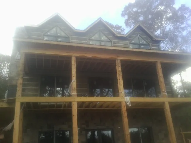 Dormers and porch framing on a large log home under construction — Roof Coating work by our crew in Patriot