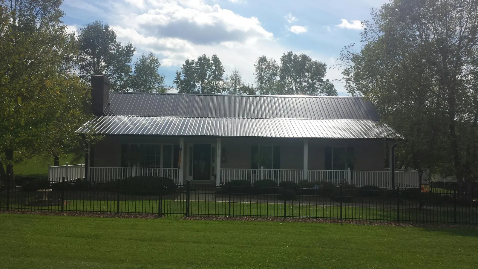 Gray metal roof on a brick ranch with a full width front porch — Gutter Guard Installation work by our crew in Patriot