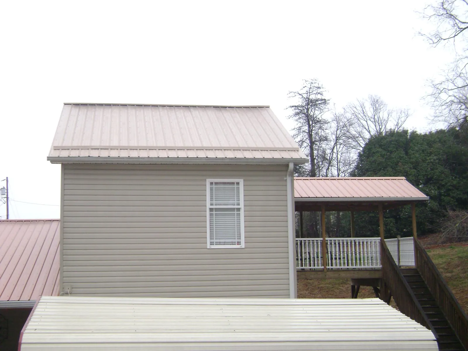 Tan metal roofs on a two story addition and attached porch, from a Roof Replacement job in Patriot